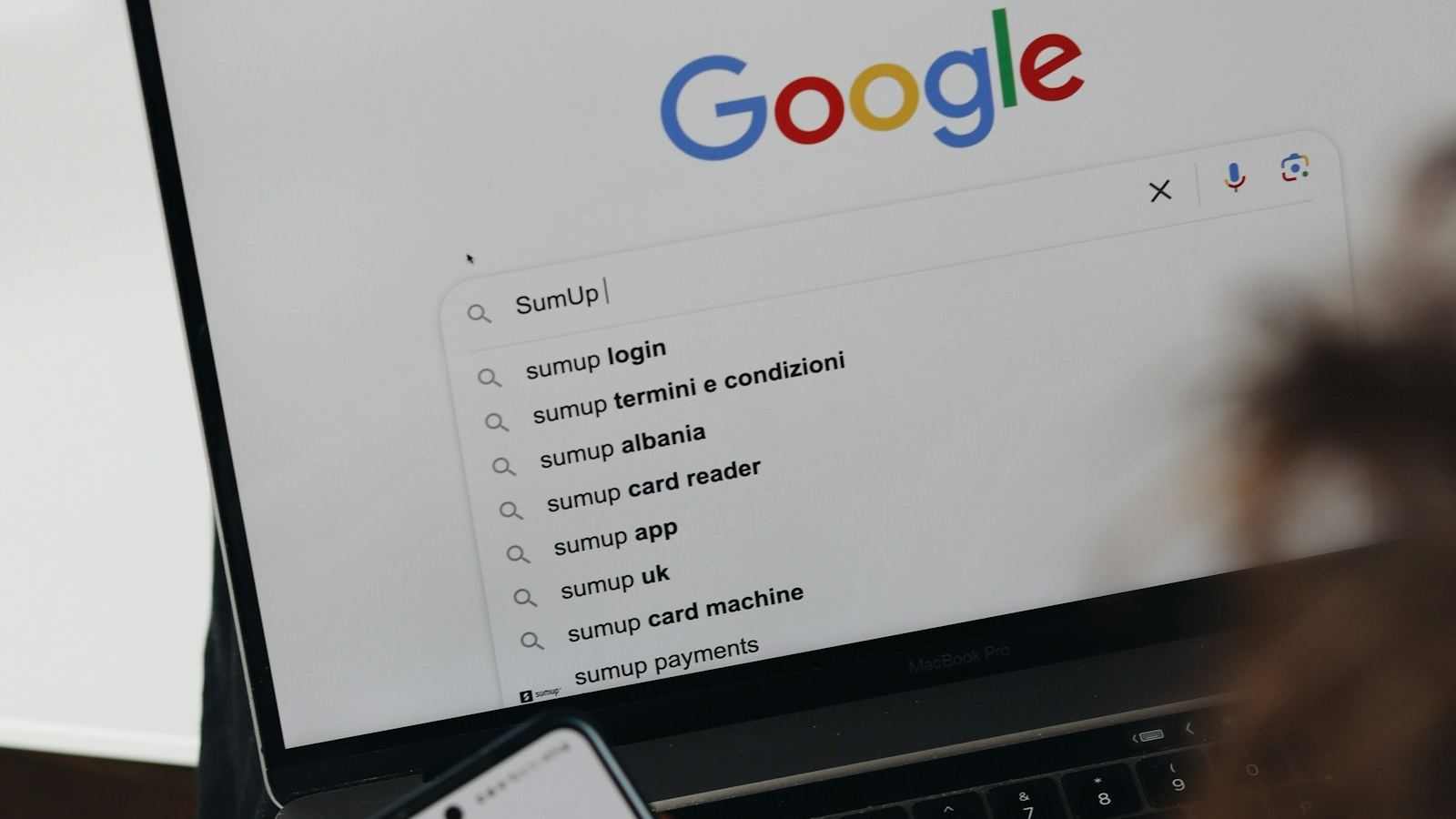 Business owner searching Google on a laptop and phone, representing Google Ads in Tunbridge Wells